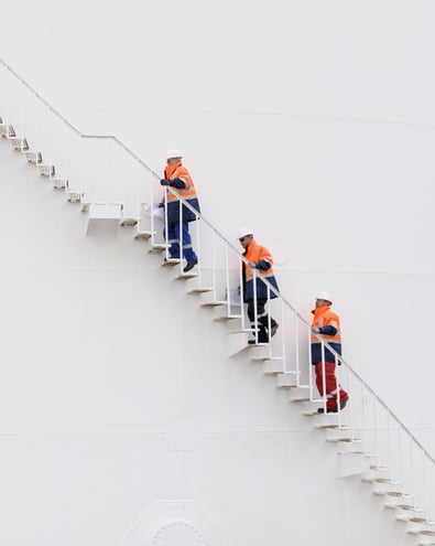 Three people climbing up the stairs, wearing safety gear - safety and quality