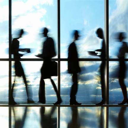 Blurred image of business people walking by window with sky behind